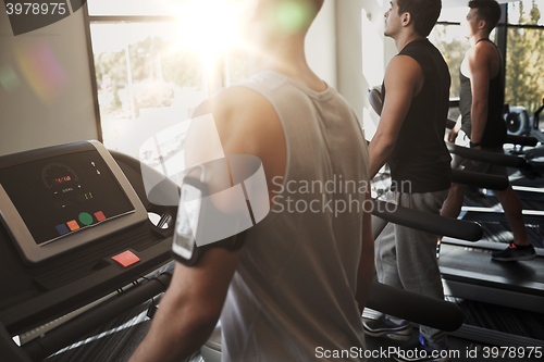 Image of smiling men exercising on treadmill in gym