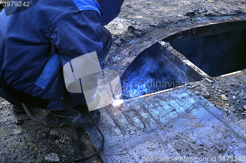 Image of Work performs welding for metal outdoors