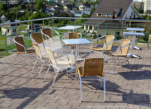 Image of Wicker chairs with metal legs and racks are in an open cafe area