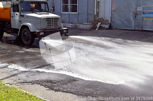 Image of Water truck watering the asphalt at a manufacturing plant for dust suppression