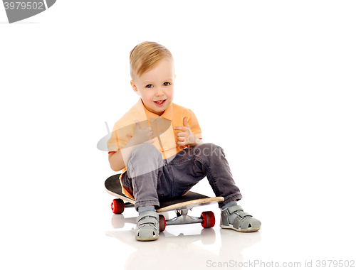 Image of happy little boy on skateboard showing thumbs up