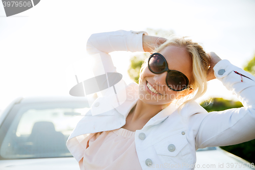 Image of happy teenage girl or young woman near car