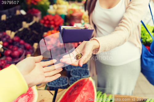 Image of pregnant woman with wallet buying food at market