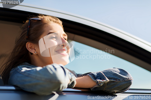 Image of happy teenage girl or young woman in car