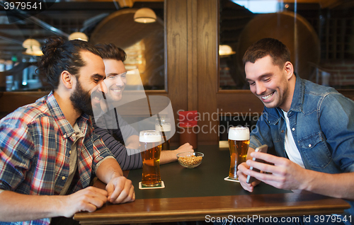 Image of male friends with smartphone drinking beer at bar