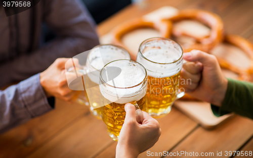 Image of close up of hands with beer mugs at bar or pub