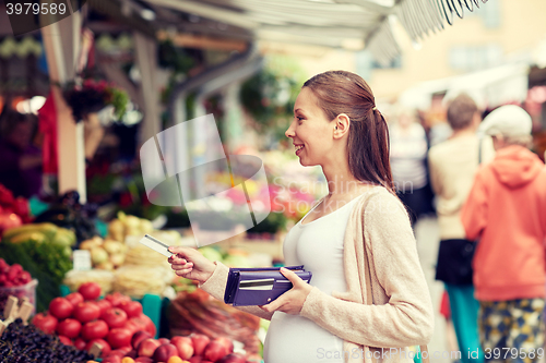 Image of pregnant woman with credit card at street market