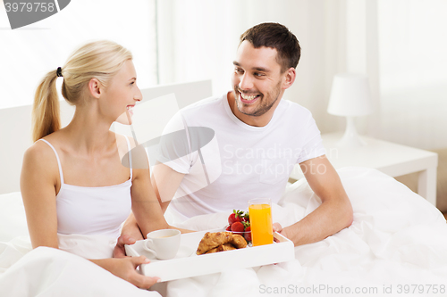 Image of happy couple having breakfast in bed at home