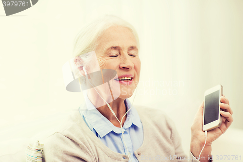 Image of senior woman with smartphone and earphones at home