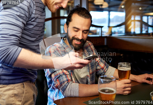 Image of men with smartphones drinking beer at bar or pub