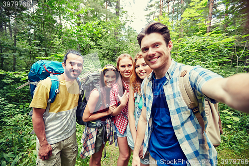 Image of friends with backpack taking selfie in wood