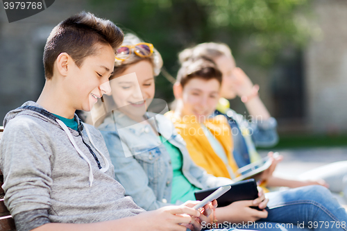 Image of happy teenage friends with tablet pc outdoors