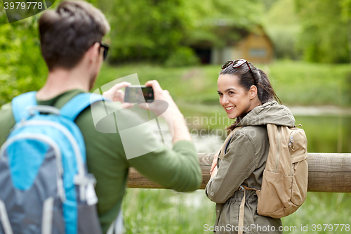 Image of couple with backpacks taking picture by smartphone