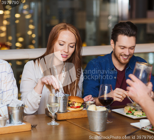 Image of man with smartphone and friends at restaurant