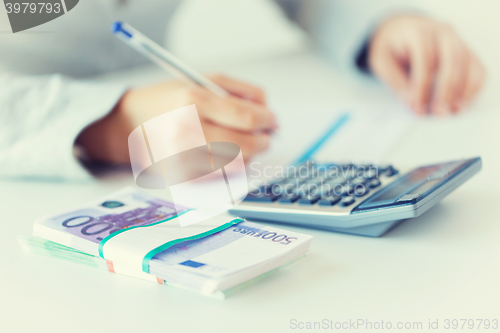 Image of close up of hands counting money with calculator