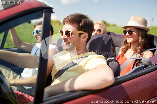 Image of happy friends driving in cabriolet car