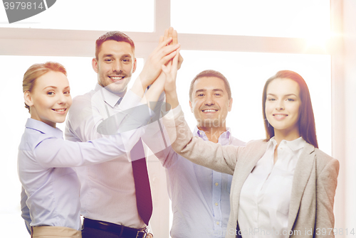 Image of happy business team giving high five in office