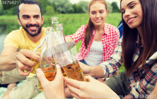 Image of happy friends with tent and drinks at campsite