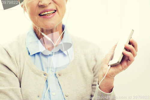 Image of happy senior woman with smartphone and earphones