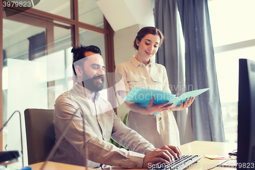 Image of happy creative team with computer in office