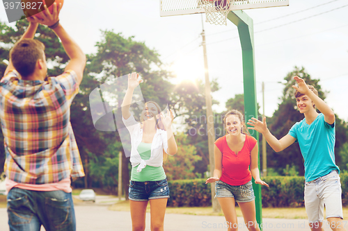 Image of group of smiling teenagers playing basketball