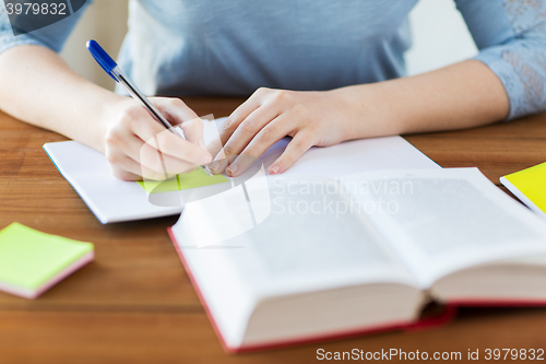 Image of close up of student with book and notebook at home