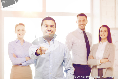 Image of businessman in office pointing finger at you