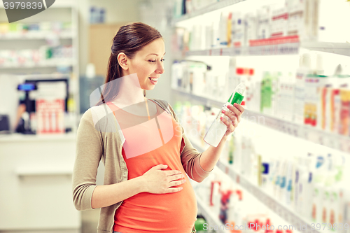 Image of happy pregnant woman choosing lotion at pharmacy