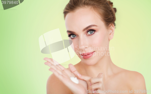 Image of happy young woman with moisturizing cream on hand