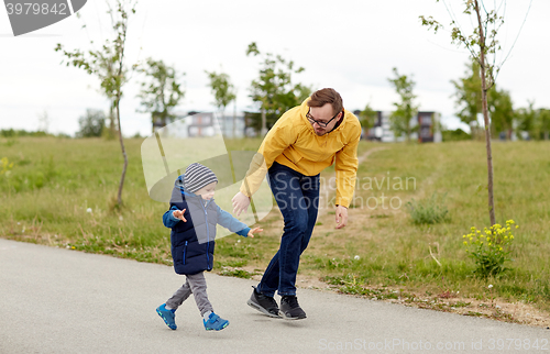 Image of happy father and little son walking outdoors