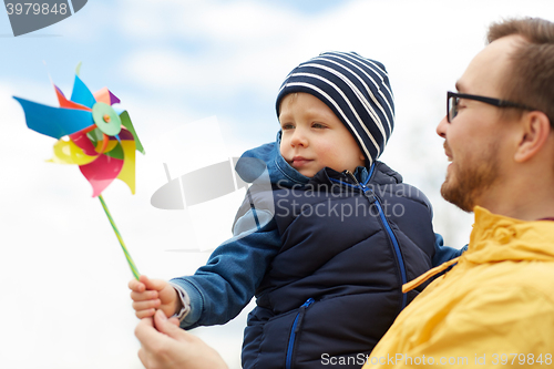 Image of happy father and son with pinwheel toy outdoors