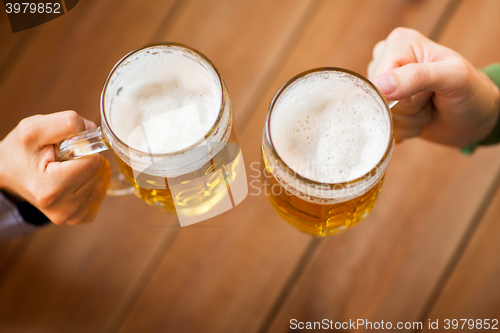 Image of close up of hands with beer mugs at bar or pub