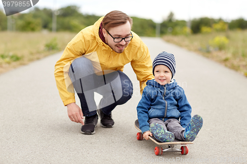 Image of happy father and little son riding on skateboard