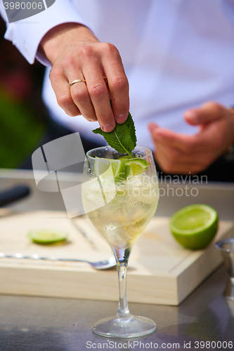 Image of Bartender in nature preparing alcoholic drink mojito.