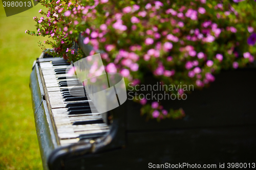 Image of Old wooden piano decorated with flowers