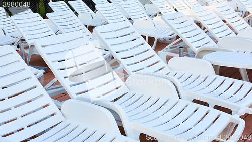 Image of number of empty sunbeds at the pool early in the morning