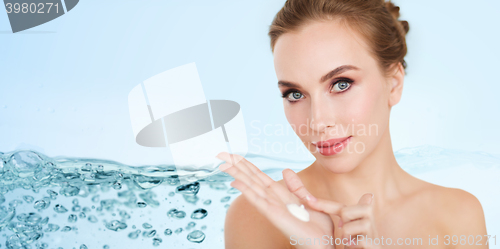 Image of happy young woman with moisturizing cream on hand