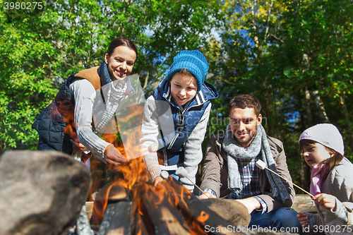 Image of happy family roasting marshmallow over campfire