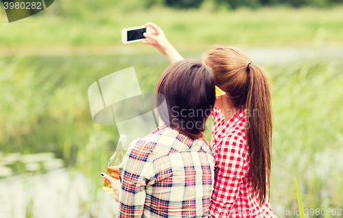 Image of happy women taking selfie by smartphone outdoors