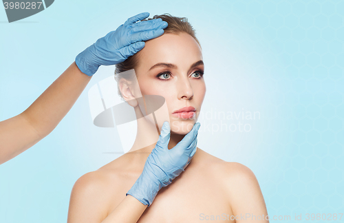 Image of surgeon or beautician hands touching woman face