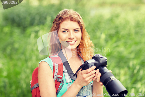 Image of happy woman with backpack and camera outdoors