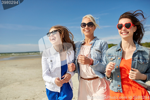 Image of group of smiling women in sunglasses on beach