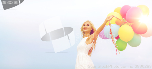 Image of smiling woman with colorful balloons outside