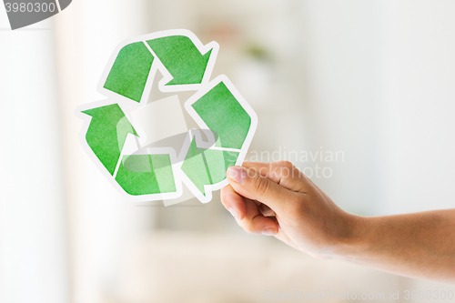 Image of close up of hand holding green recycle symbol