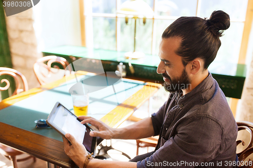 Image of man with tablet pc drinking beer at bar or pub