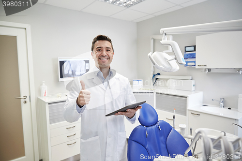 Image of happy dentist showing thumbs up with tablet pc