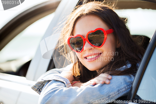 Image of happy teenage girl or young woman in car