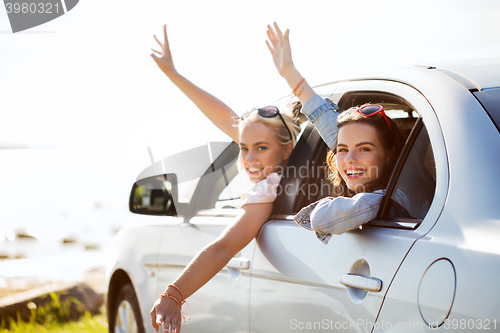 Image of happy teenage girls or women in car at seaside