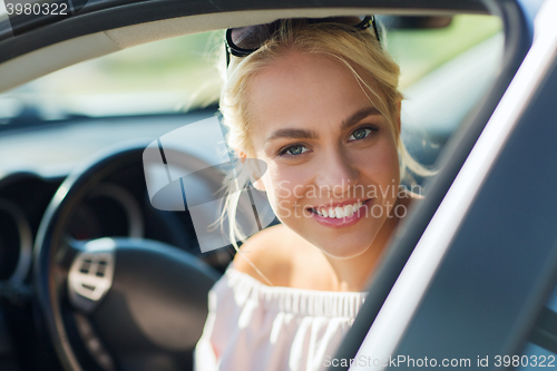 Image of happy teenage girl or young woman in car