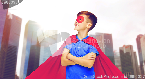 Image of boy in red superhero cape and mask over city